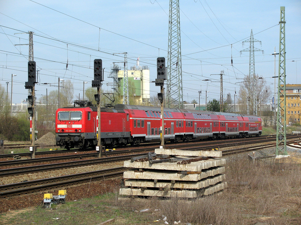 143 210-3 kam bei feinem Fr�hlingssonnenlicht in den Bahnhof Berlin Sch�nefeld Flughafen eingefahren und passiert dabei einen abgelegten Schwellenstapel.