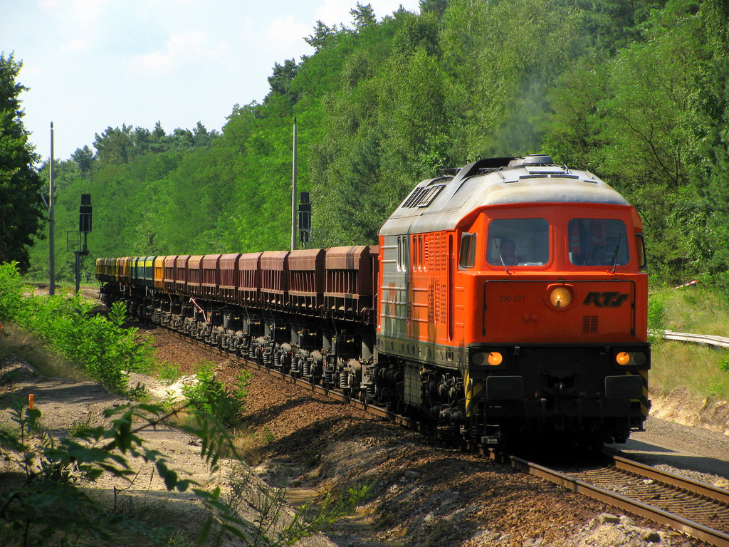 230 077 der RTS mit einem Abraumzug am 27.07. auf dem Weg durch Bestensee gen Norden.