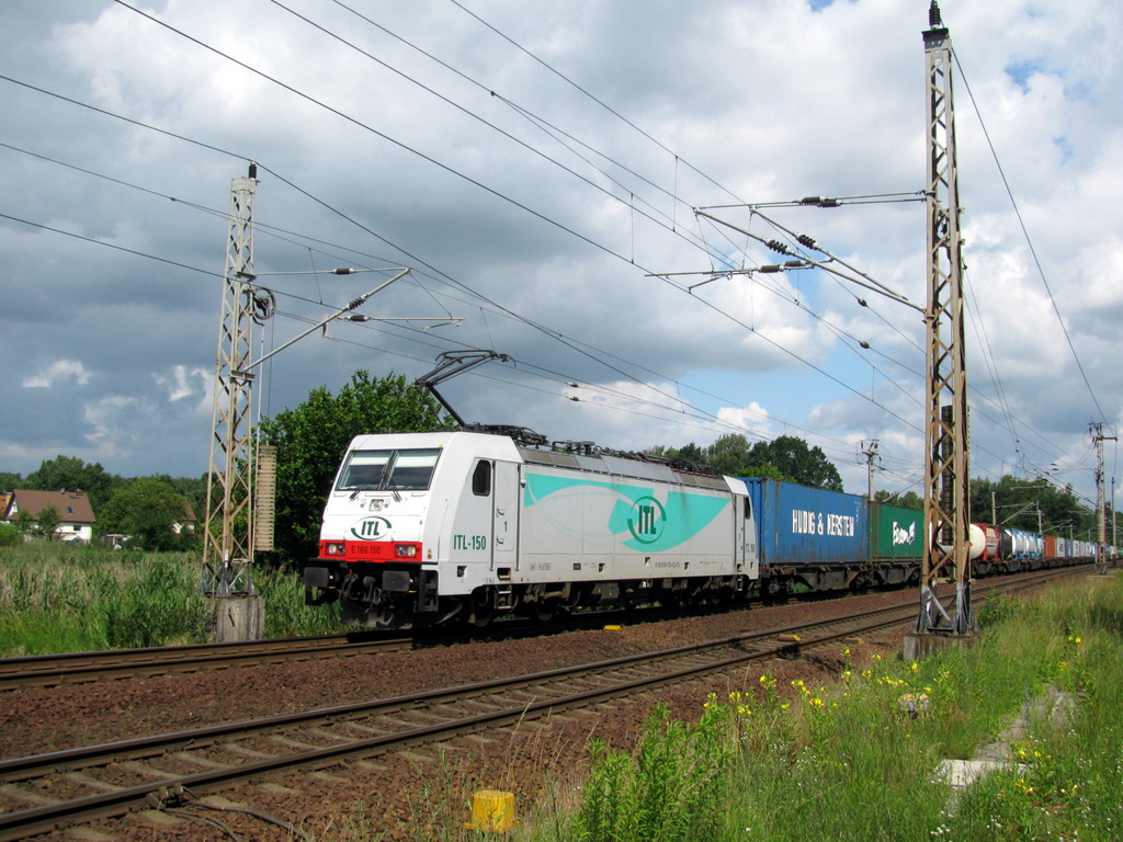 Der schiefste Mast der Welt ist wohl links zu sehen, aber darauf kommt es nicht an. Im Bild ist die ITL 186 150 mit einem sehr langen Container GZ durch Bestensee um 10:48 am 20.06. Mittlerweile ist diese Lok f�r Captrain Benelux im Einsatz.