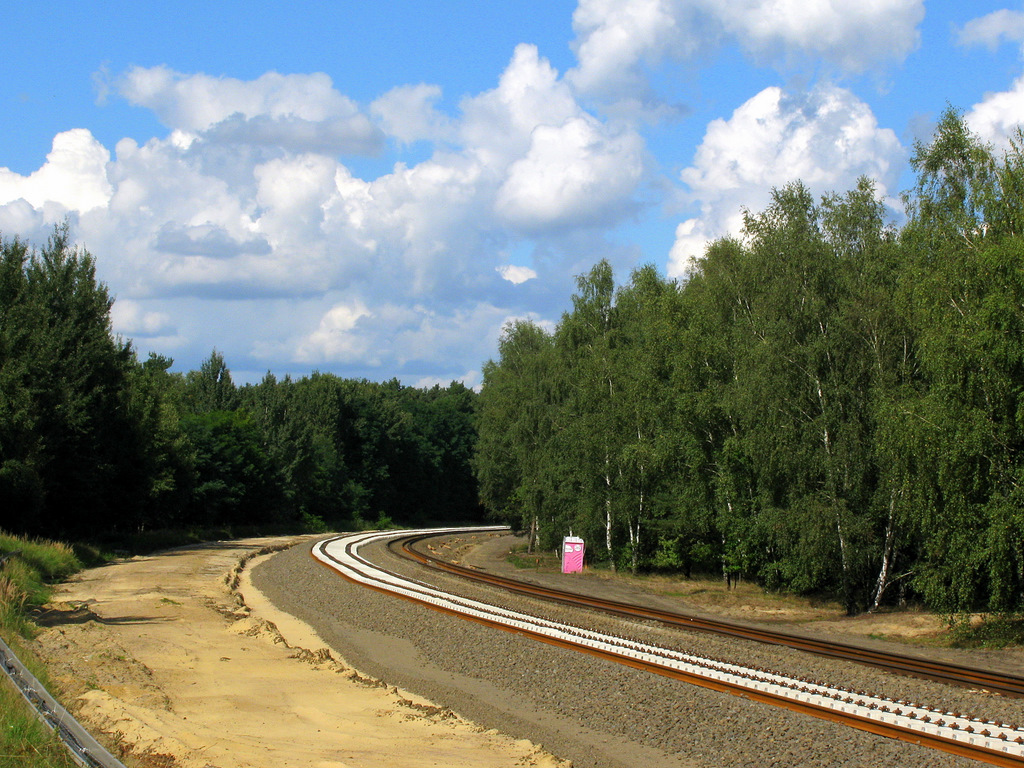 Hier ein Bild vom Zustand der Baustelle am 05.09. zwischen Bestensee und Gro� K�ris. Hier wird mitten im Wald eine Kurve neu verschwenkt. Das Sandbett, war die alte Lage, dahinter die neue mit den neuen Schwellen. Die neuen Schwellen sind ganz besondere: Es sind sogenannte  Fl�sterschwellen , welche weniger Ger�usche und Vibrationen �bertragen. Die Bahn montiert diese erstmals Deutschlandweit auf einer ganzen Strecke (bisher gab es dies nur zu Testzwecken).