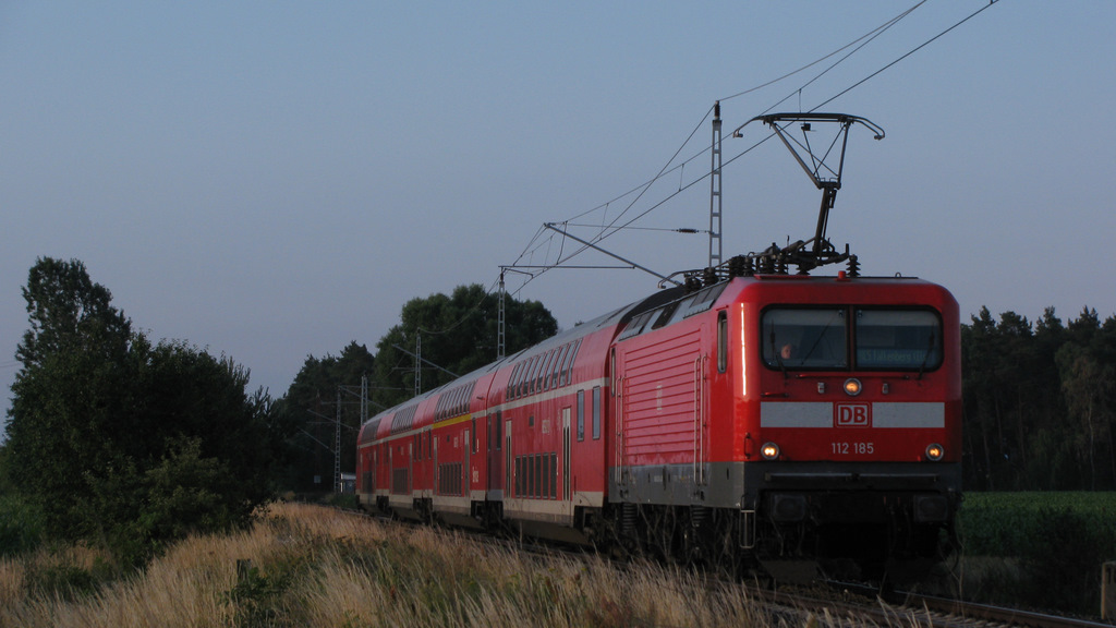 Wenn wir nicht um 3:30 Uhr aufstehen w�rden, dann w�re dieses Bild zwischen Falkenberg(Elster) und Herzberg nie entstanden. Es zeigt den RE5 (RE 18506) von Falkenberg nach Stralsund mit knapp 10 Minuten Versp�tung aus der vorherigen Fahrt. Scheinbar war bei der Kurzwende in Falkenberg nicht mal Zeit die Anzeige und den Panto zu wechseln ;-) . 01.07.2011